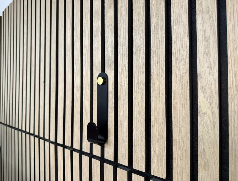 Patère en métal noir fixée sur un panneau rainuré